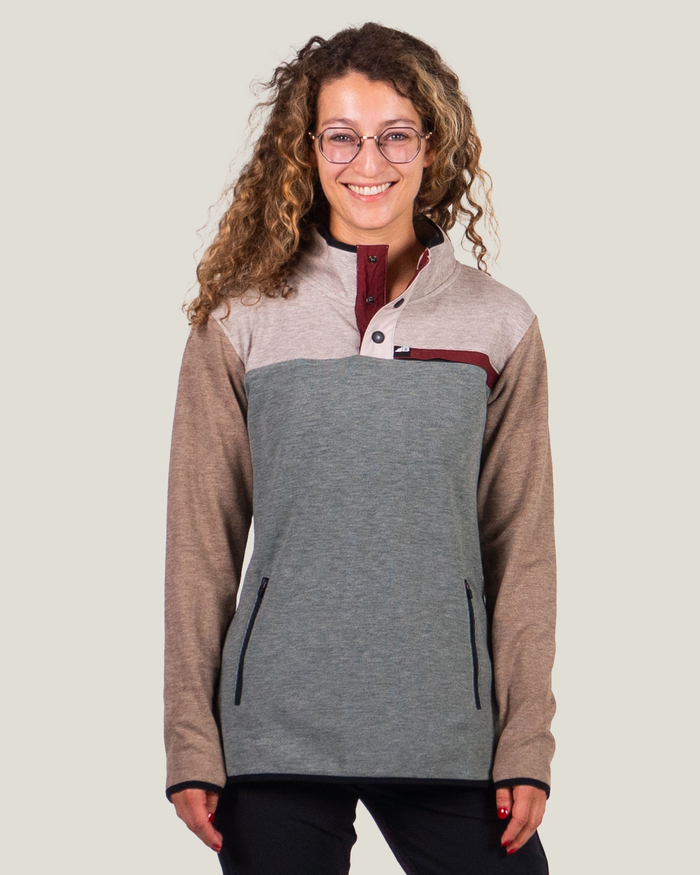 Woman wearing a gray and brown pullover with a plain background