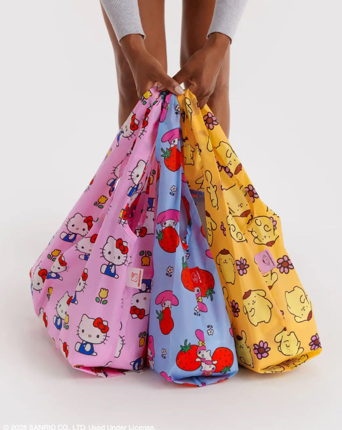Three colorful Hello Kitty bags held by a person on a white background