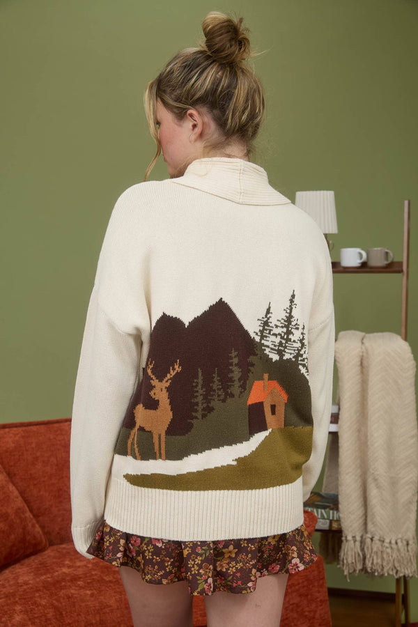 Woman wearing a sweater with a nature-themed design in a cozy room.