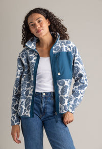 Woman wearing a blue and white patterned jacket on a gray background