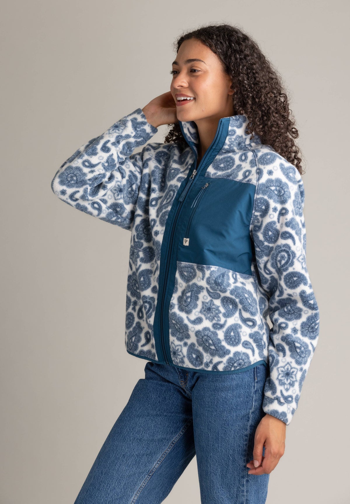 Woman wearing a blue and white patterned jacket with a visible brand logo on a beige background
