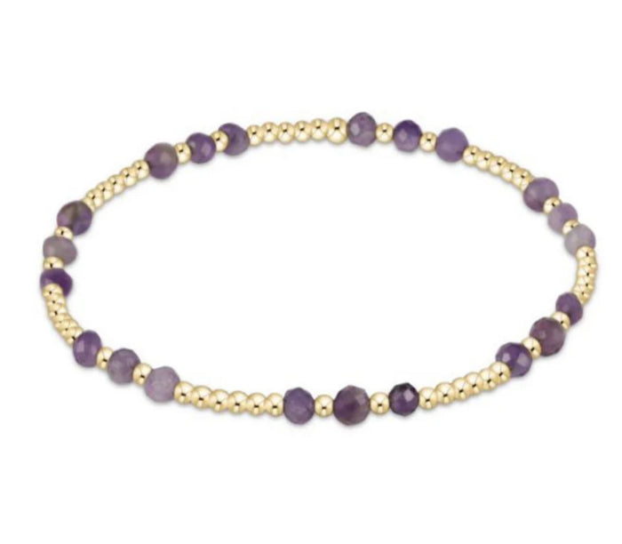 Bracelet with purple beads and gold accents on a white background
